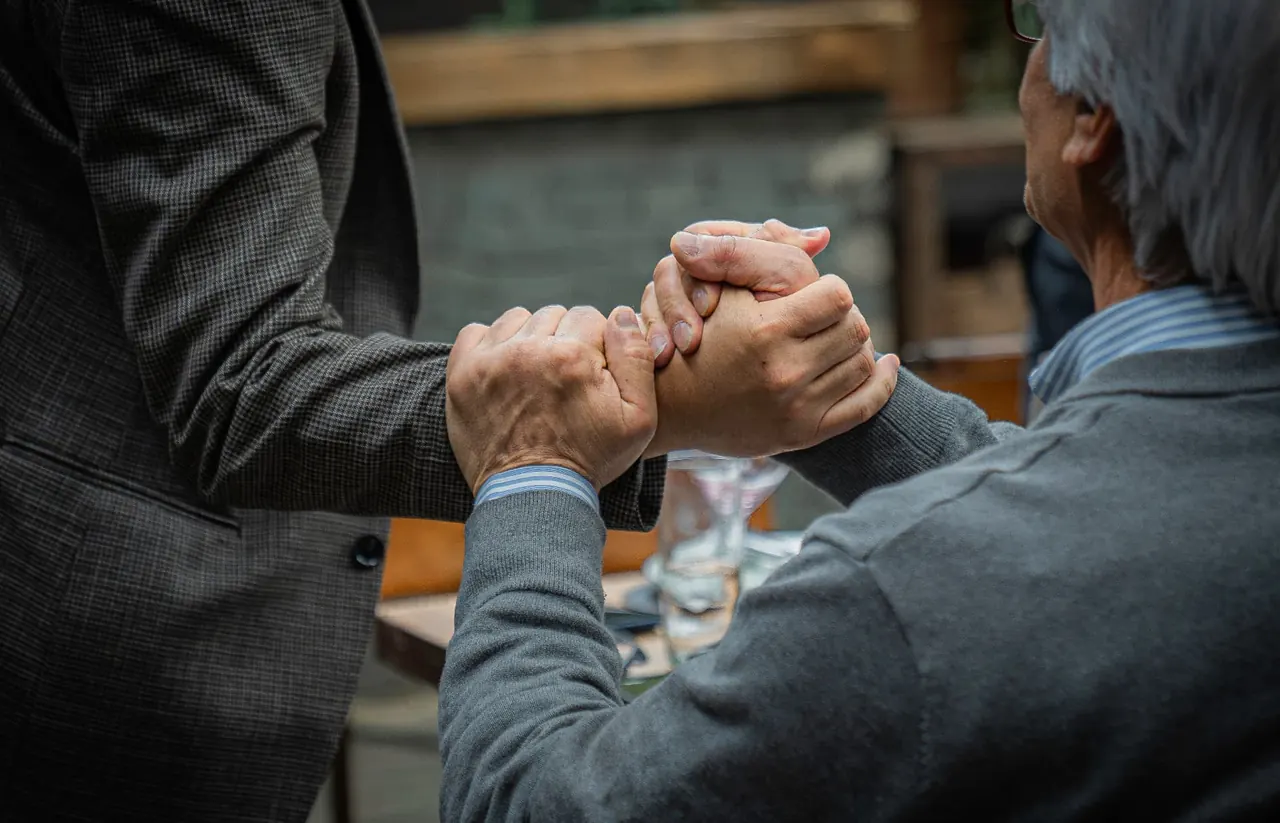 Dos empresarios estrechándose la mano sobre una mesa de reunión